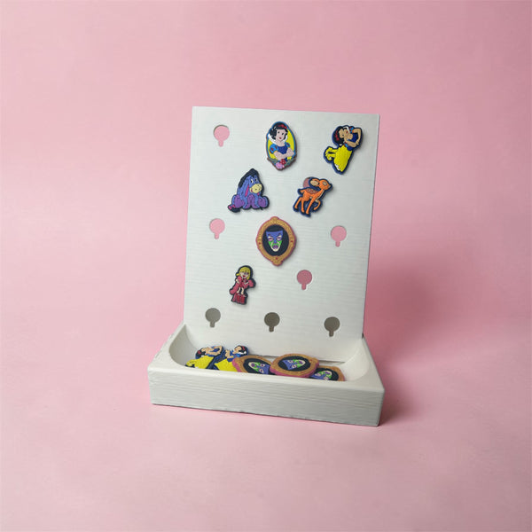 NiccieNacks Croc Jibbitz charm display stand shown with colorful charms on a home decor surface.